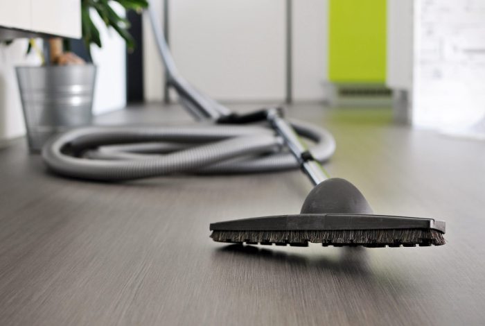 Central vacuum cleaner hose laid on the floor in the living room. Cleaning room conceptual shot, focused on foreground.